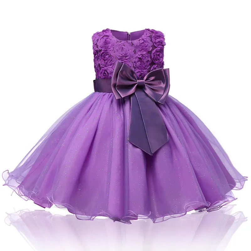 Purple sleeveless dress with a floral bodice, sparkly tulle skirt, and large satin bow at the waist. Perfect for special occasions or parties.