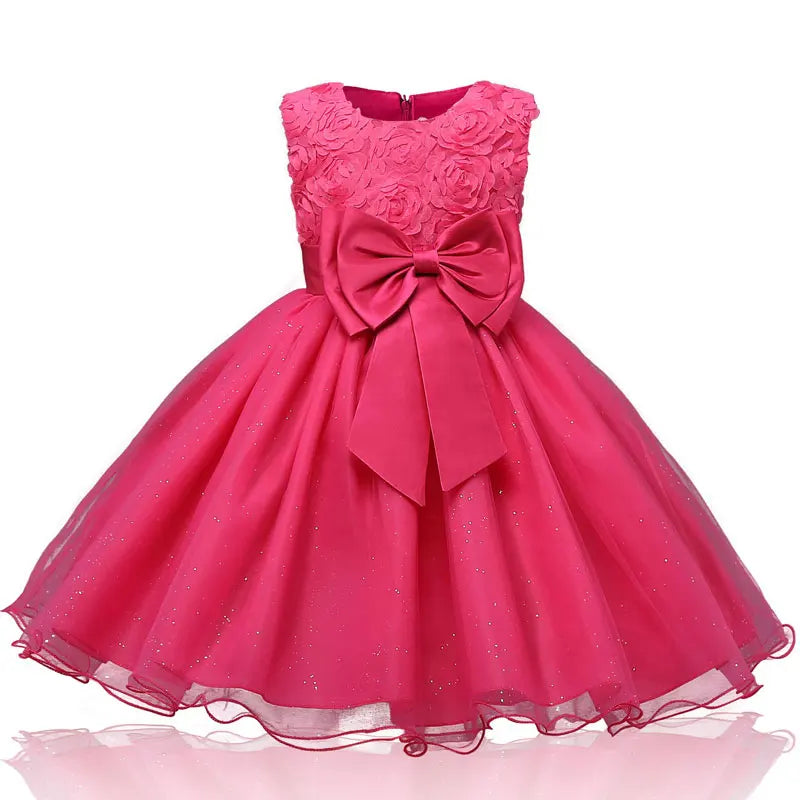 Pink sleeveless dress with floral detailing on the bodice and a large bow at the waist. The skirt is full and sparkling, giving a princess-like appearance.