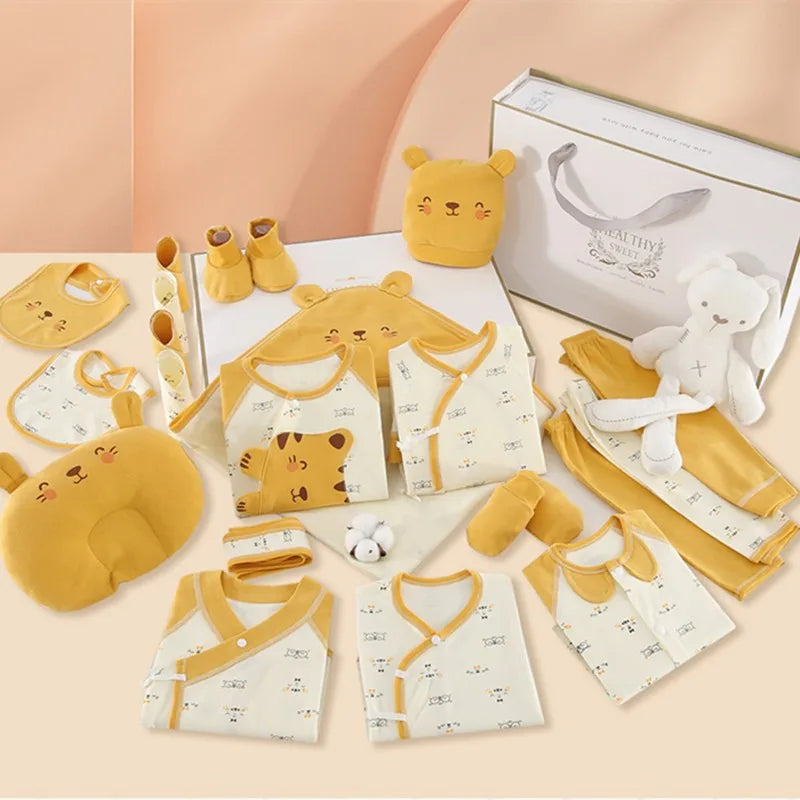 A baby gift set with yellow and white clothing featuring bear motifs, includes a pillow, bibs, onesies, mittens, socks, hat, and a plush toy, all neatly arranged with a gift box.