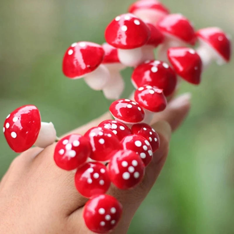 A hand adorned with red and white spotted mushroom-shaped decorations, resembling a cluster of toadstools against a blurred green background.