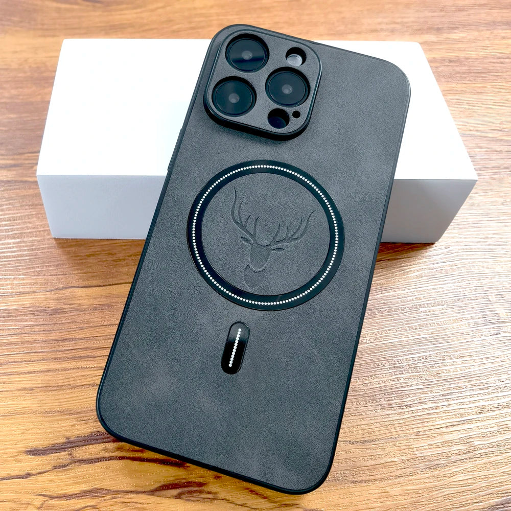 A smartphone with a black case featuring a deer head design and a circular pattern. The phone is placed on a wooden surface, leaning on a white box.