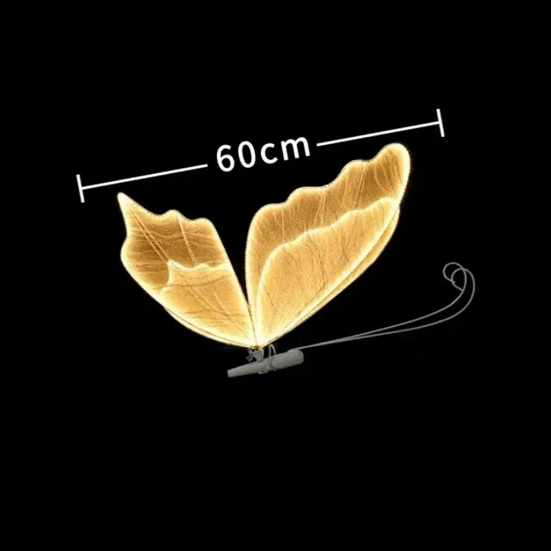 Golden butterfly leaves with a 60 cm span on a black background, resembling fairy wings. A thin connection and wire are attached at the base.