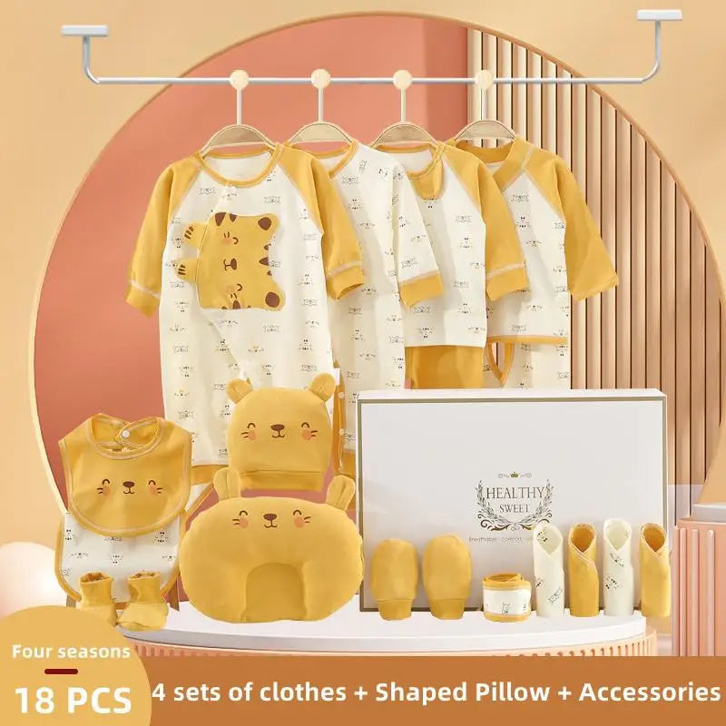Baby gift set with 18 pieces, featuring four sets of clothes with bear designs, a shaped pillow, bib, socks, mittens, and accessories, arranged aesthetically on a peach background.