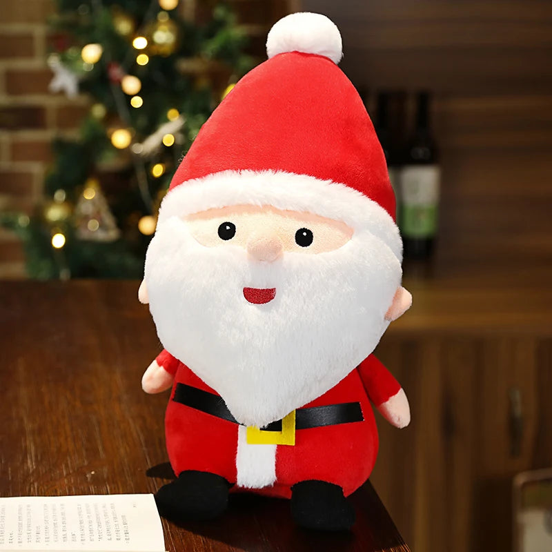 A plush Santa Claus toy with a red hat and white trim sits on a wooden table. A Christmas tree with lights is in the background.