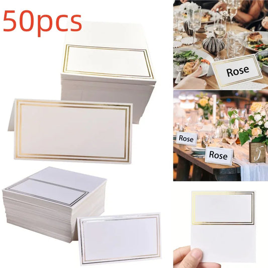 Set of 50 blank place cards with gold borders, displayed stacked and individually. Example shows cards used at a dining table with elegant decor and flowers.
