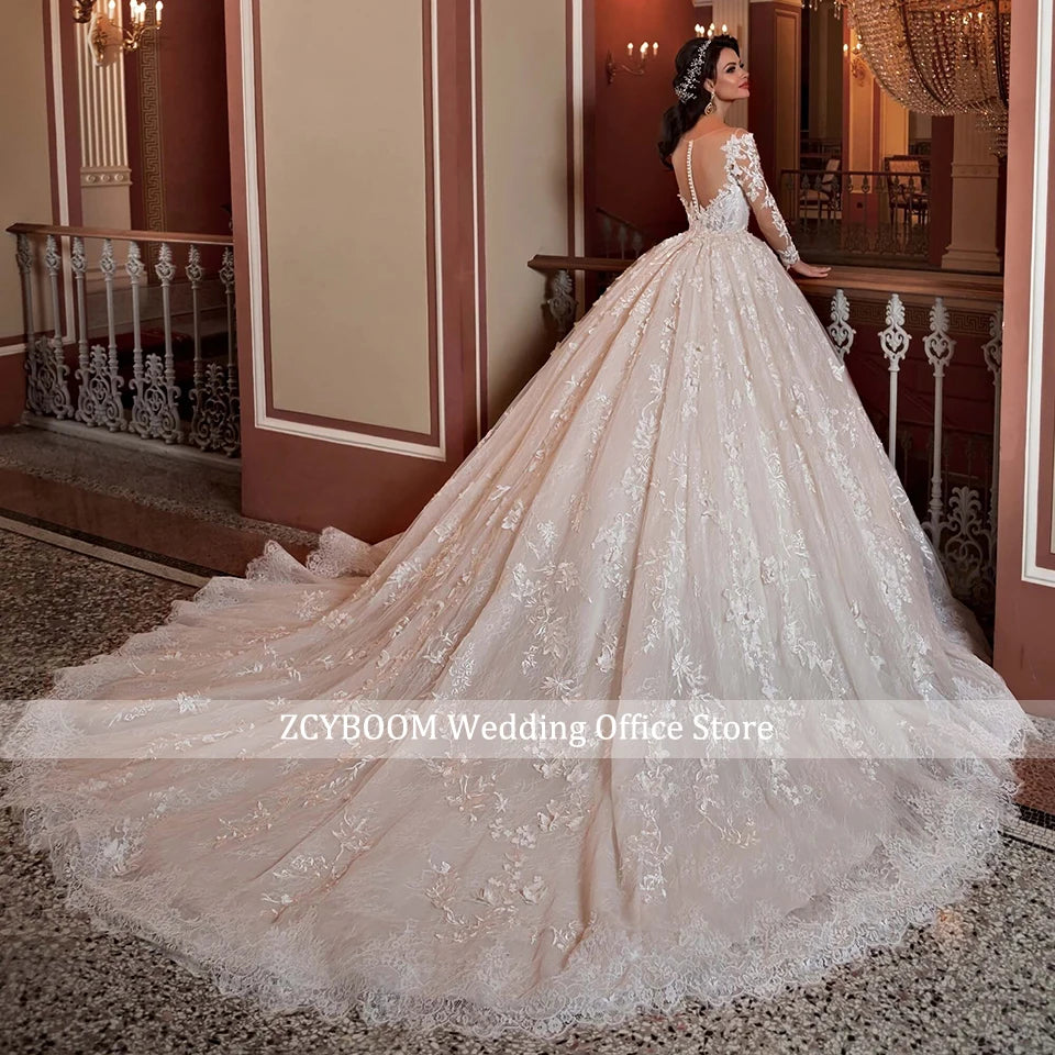 A bride in an elegant ballroom stands holding a railing, wearing a lace-embellished gown with a long train. The ornate hall features chandeliers, marble floors, and classical decor.