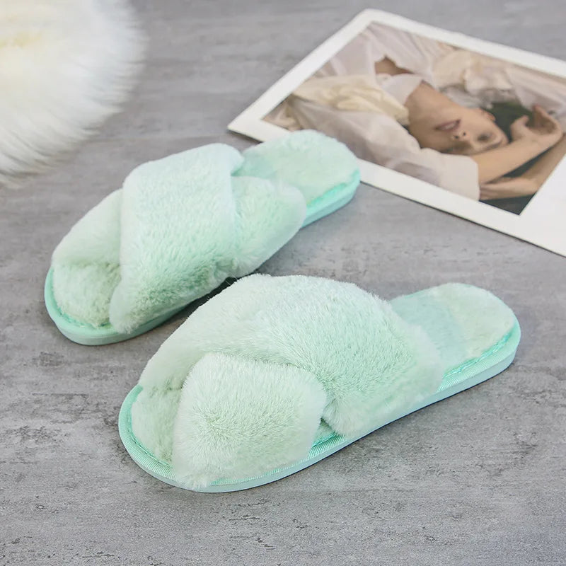 Mint green fuzzy slippers with crisscross straps are placed on a gray surface next to a magazine showing a reclining woman in soft, neutral colors.