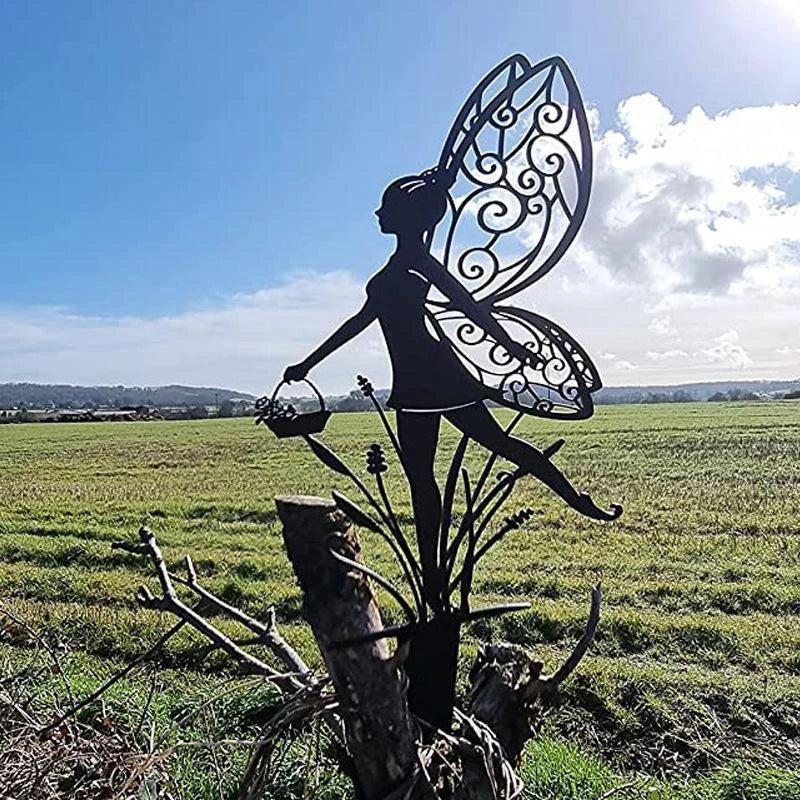 Silhouette of a decorative fairy with ornate wings and a basket, placed on a wooden post. The background features a vast green field under a clear blue sky.