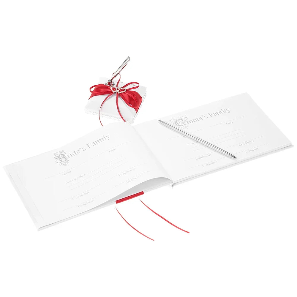 Open wedding guest book with sections for bride and groom's families, accompanied by a sleek pen. A decorative pen holder with red ribbon and embellishment sits nearby.