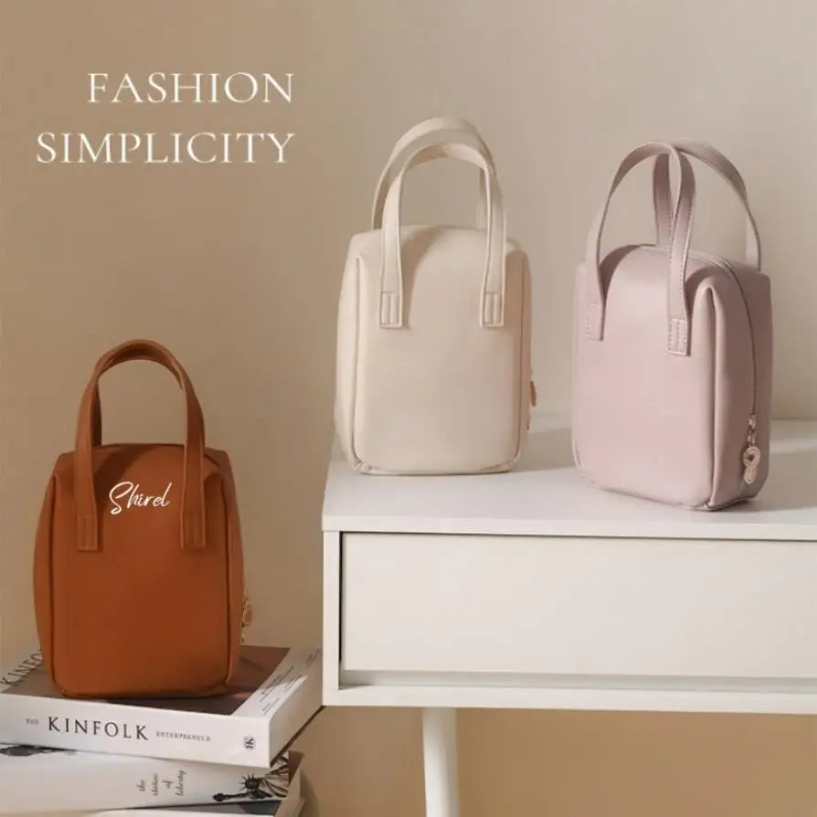 Three minimalist handbags in brown, cream, and pink displayed on a white desk and stacked books. Background text reads "Fashion Simplicity."