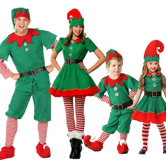 Four people dressed as Christmas elves in green and red outfits with striped stockings. Two adults and two children stand smiling, wearing pointy hats and elf shoes.