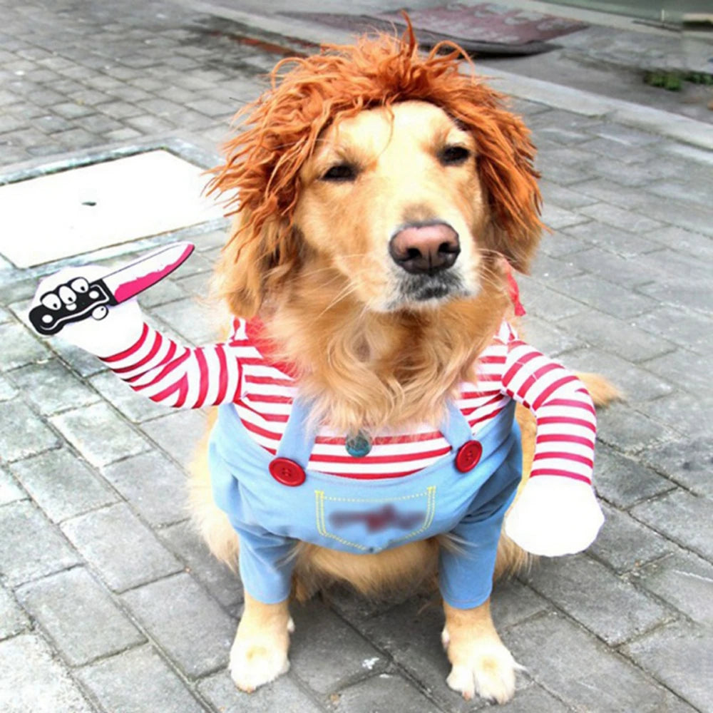 Golden retriever wearing a red wig and a striped outfit, dressed as a doll, holding a fake knife. The dog is sitting on a paved area, looking directly at the camera.