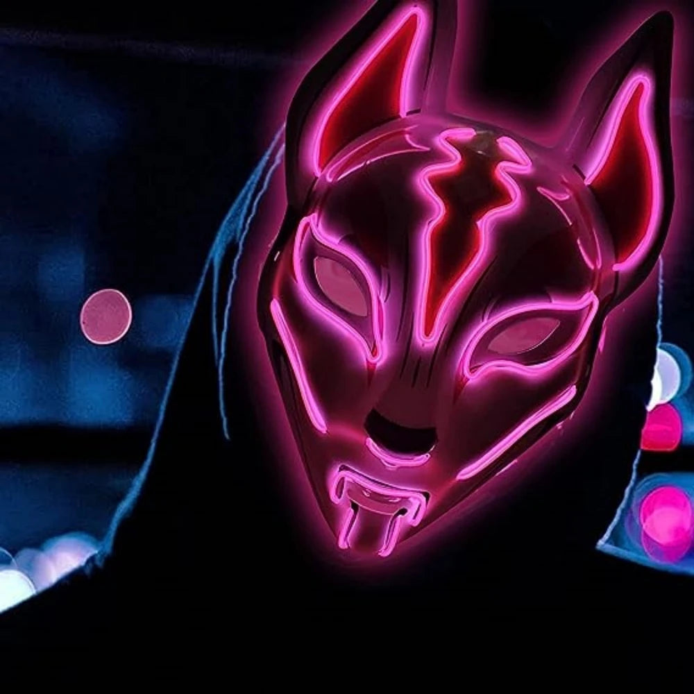 Person in a dark setting wearing a glowing, neon pink mask resembling a fox. The mask has intricate designs and pointed ears, with a hooded figure in the background.