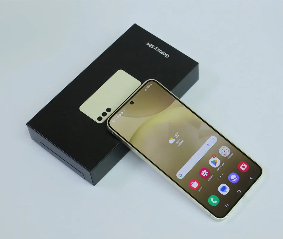 Smartphone with gold screen and app icons displayed, resting on a black Galaxy S24 box with a minimalist design.