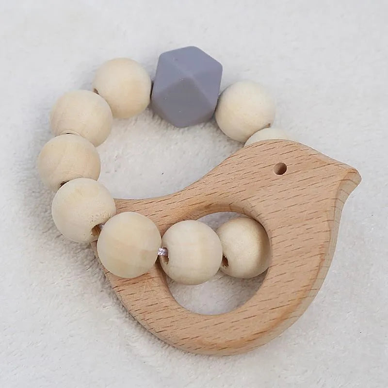 Wooden bird-shaped teether with natural wood beads and a single gray geometric bead, arranged in a circle, displayed on a soft white background.