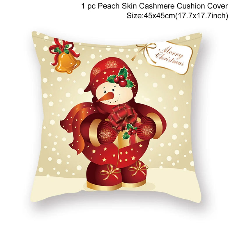 Festive cushion cover featuring a snowman in a red outfit with holly and gifts, against a beige snowy background. "Merry Christmas" tag and bell with ribbon are also shown.