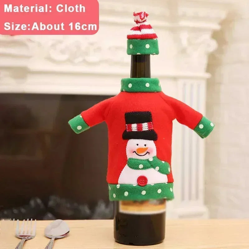 A wine bottle wears a festive red and green sweater featuring a snowman design, complete with a matching hat. The background shows a fireplace. Size: about 16cm. Material: cloth.