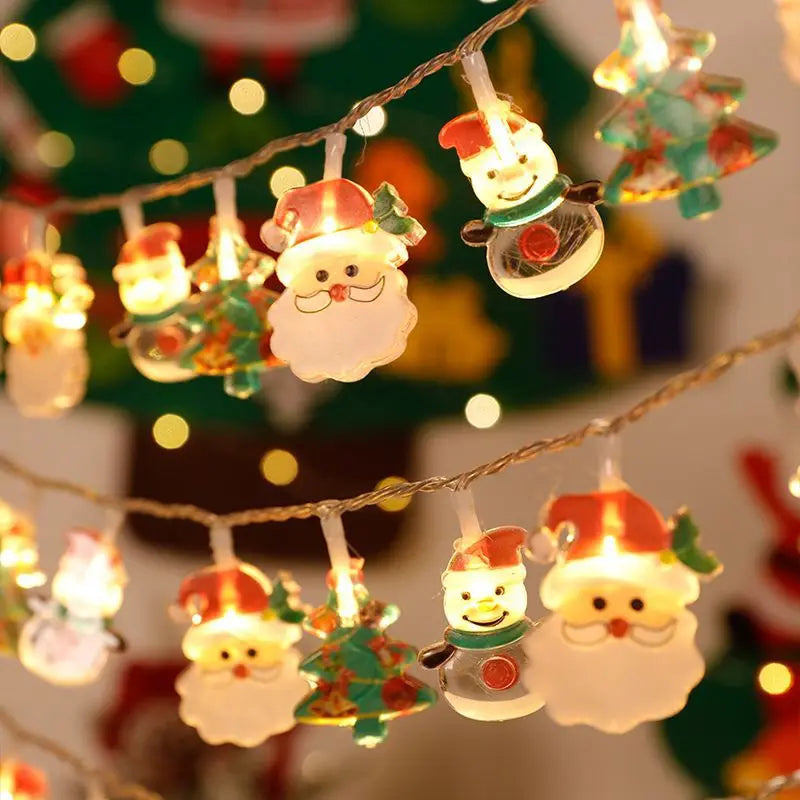 Festive string lights featuring Santa Claus, snowmen, and Christmas trees glow warmly, with a decorated Christmas tree background blurred by bokeh lighting effects.