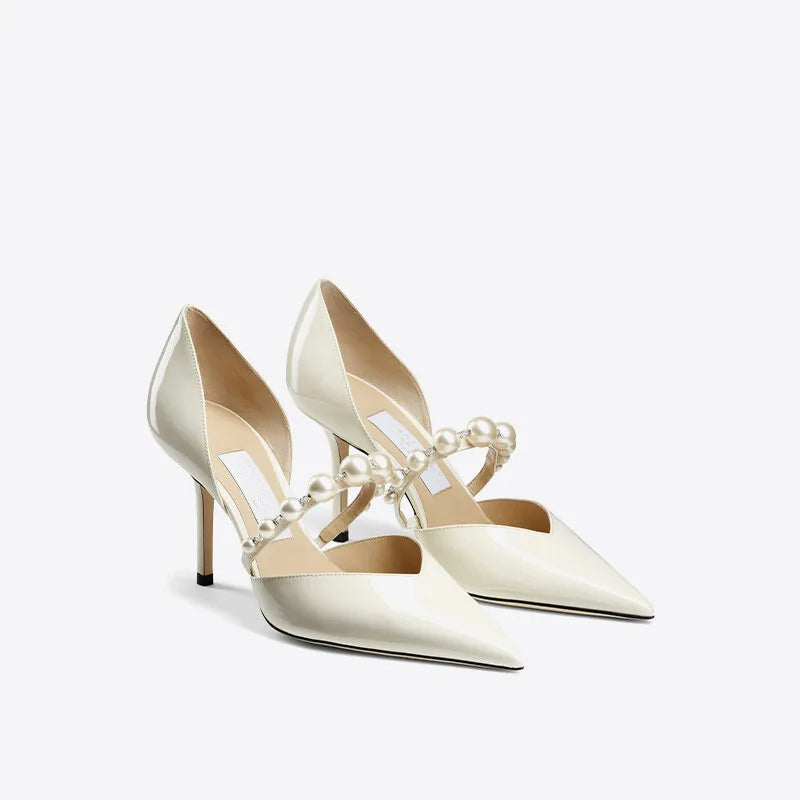 Elegant ivory high heels with pointed toes, featuring pearl-embellished cross straps.