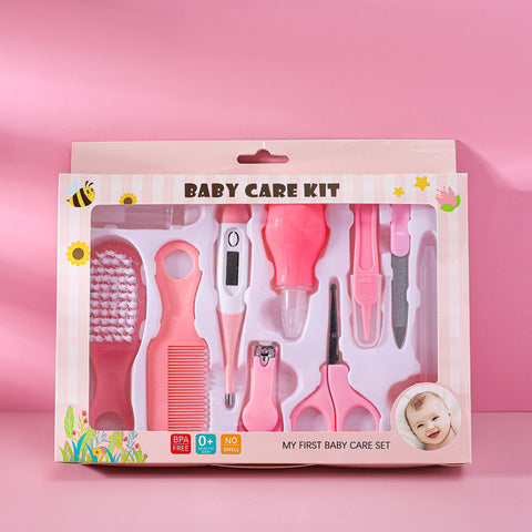 Baby care kit against a pink background, includes a pink brush, comb, thermometer, nasal aspirator, dropper, nail clippers, scissors, and tweezers. Packaging shows a smiling baby photo.