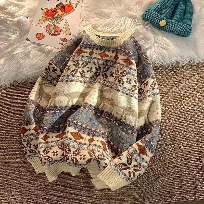 Cozy patterned sweater with reindeer and geometric designs, placed on a textured surface. Nearby are a teal beanie and a drawing of a person eating noodles.
