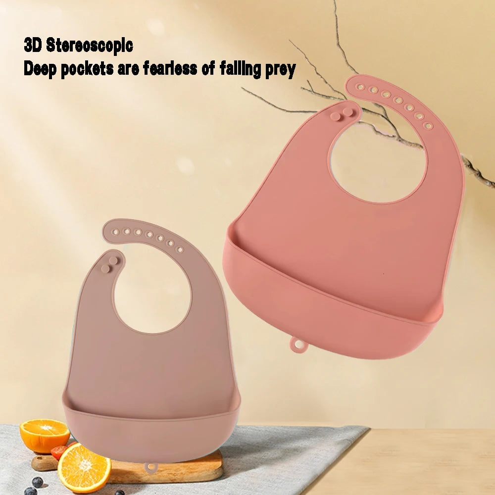 Two silicone bibs with deep pockets are displayed against a beige background. Text reads, "3D Stereoscopic, Deep pockets are fearless of falling prey." Fruits are in the foreground.