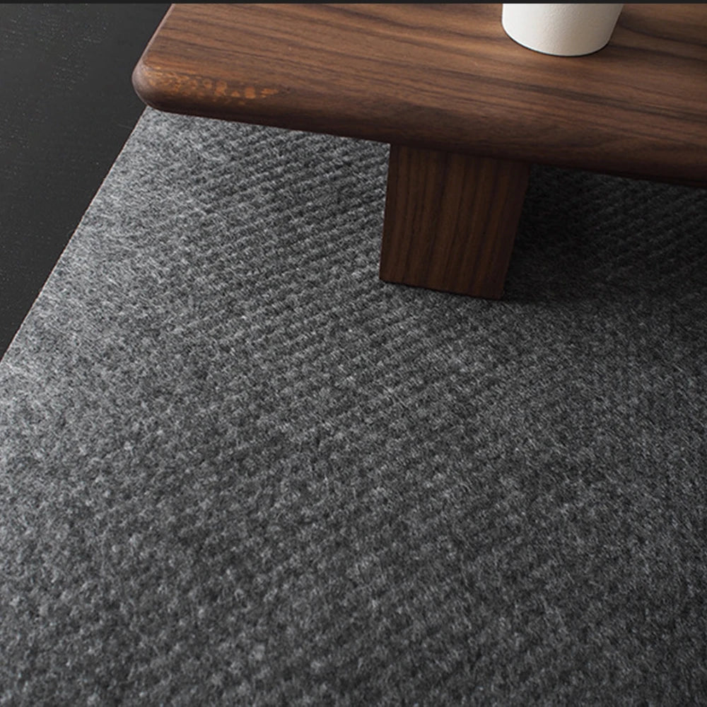Close-up of a corner of a wooden table with brown legs on a textured gray carpet. A white cylindrical object is partially visible on the tabletop.