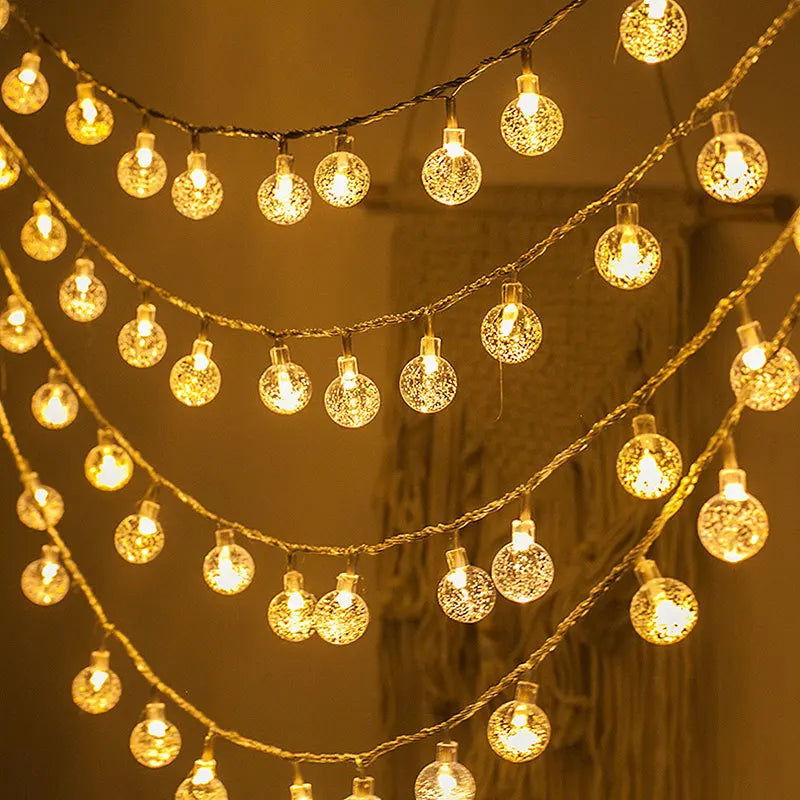 Warm yellow fairy lights with spherical, textured bulbs are strung in rows, creating a cozy, inviting ambiance against a blurred background.