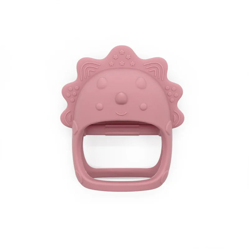 Pink silicone teether shaped like a lion’s face with a handle, featuring small embossed stars and patterns on the mane. Designed for infants to soothe teething discomfort.
