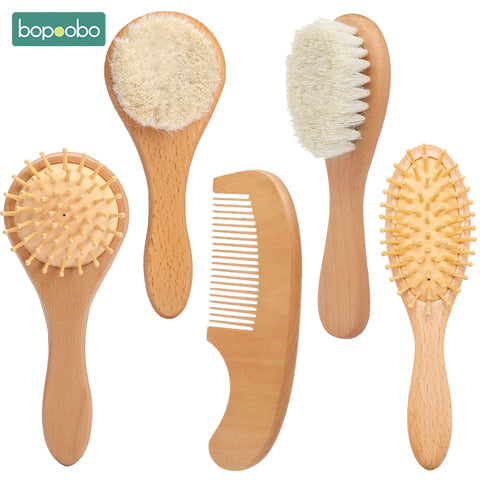 Five wooden hair tools are displayed, including two bristle brushes, two rubber-tipped brushes, and a smooth-toothed comb, all arranged on a plain white background.