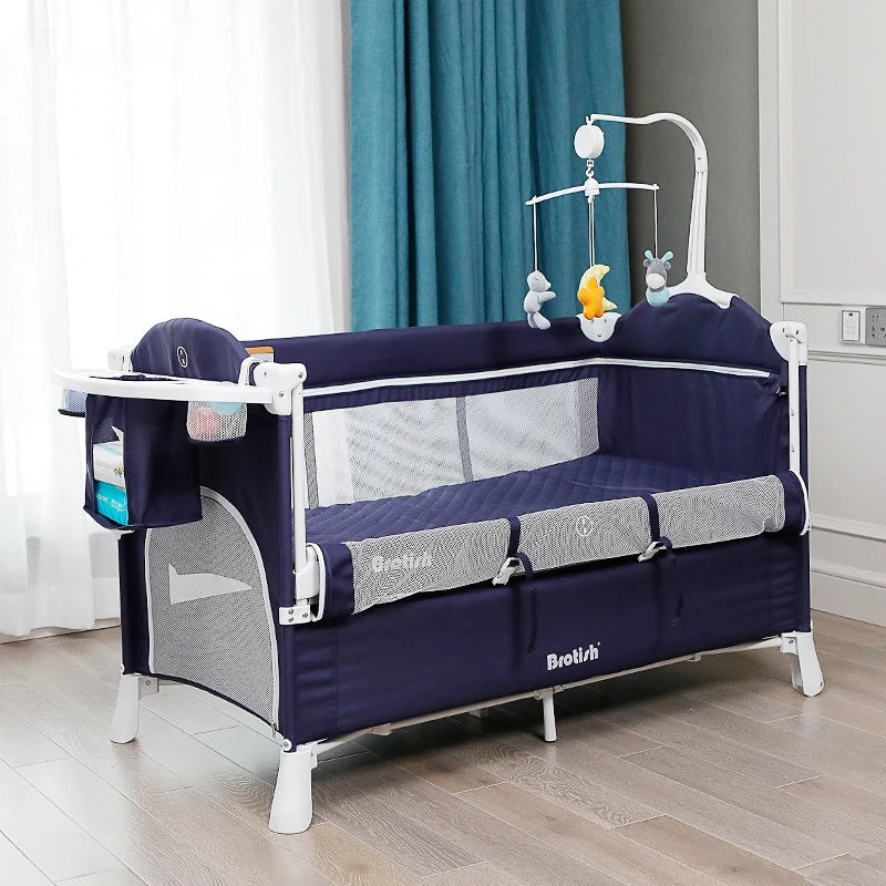 Navy blue baby crib with mesh sides, a hanging mobile with stuffed animals, and an attached side organizer. It is placed on a wooden floor with blue curtains in the background.