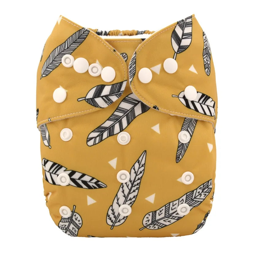 A mustard-yellow cloth diaper with a black and white feather pattern, featuring white snap closures for adjustable fitting.