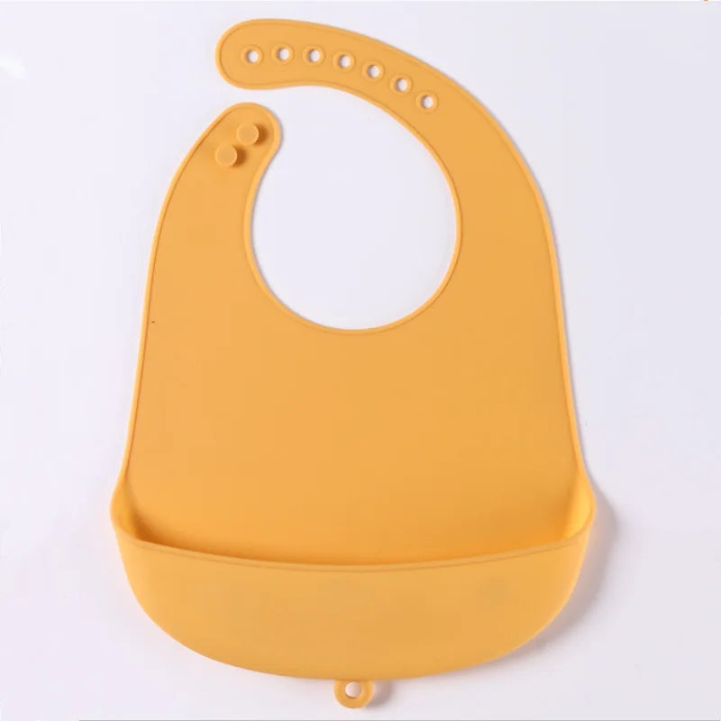 Yellow silicone baby bib with adjustable strap and a wide pocket to catch spills, laid flat on a white background.