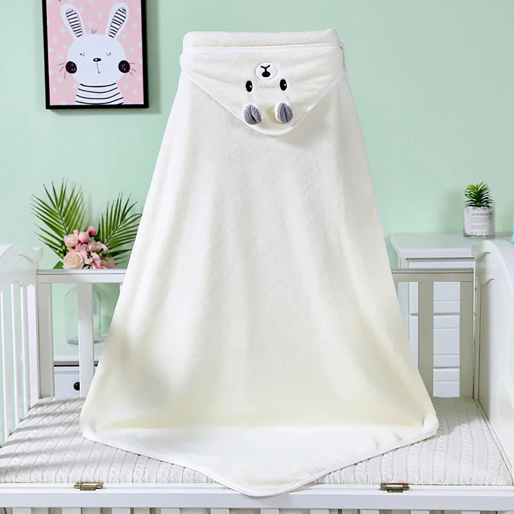 Creamy white blanket with a cute animal face and ears, draped over a crib. Soft green wall with bunny artwork and plants in the background. Cozy nursery setting.
