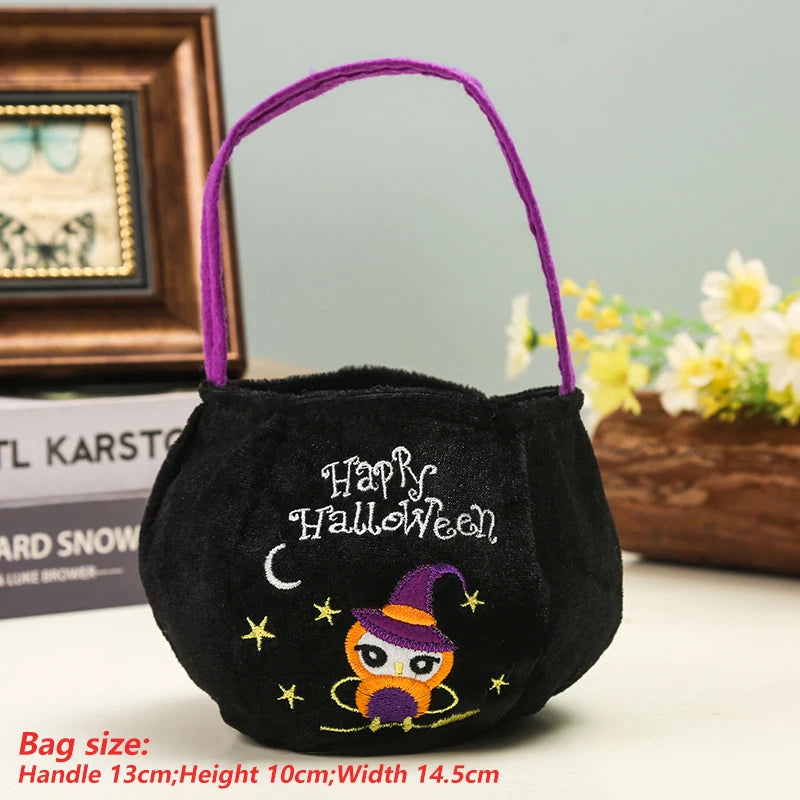 Black Halloween-themed bag with "Happy Halloween" text, a cartoon owl wearing a witch hat, and stars. Purple handle, dimensions listed. Books and flowers in the background.