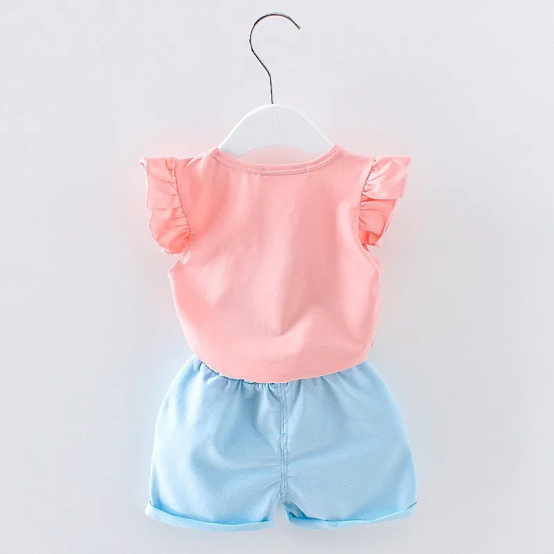 Pink ruffled sleeveless top paired with blue shorts, displayed on a hanger against a white background. The outfit is suitable for casual wear.