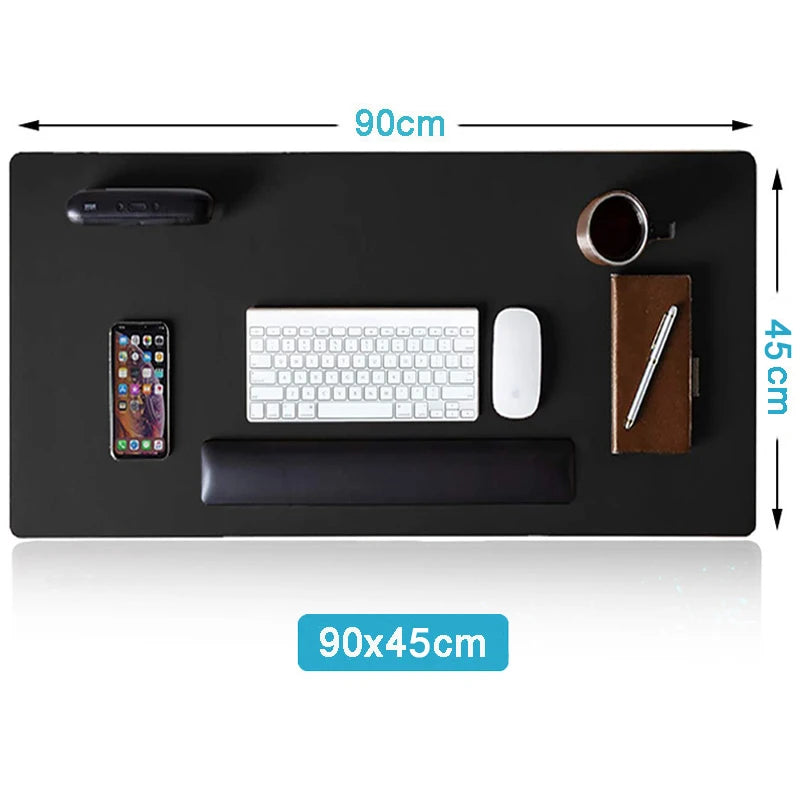 Overhead view of a 90x45cm black desk mat holding a keyboard, mouse, smartphone, cup, pen on a notebook, speaker, and wrist rest.