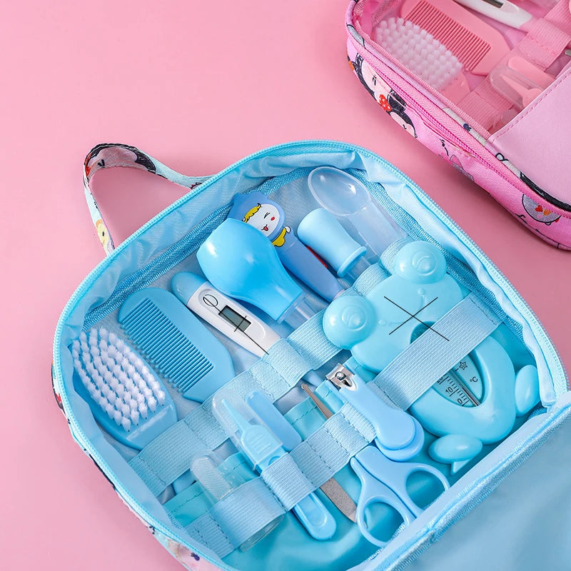 Pink and blue baby grooming kit with a brush, comb, thermometer, nasal aspirator, nail clipper, scissors, and a medicine dropper, all neatly organized in a zipper case.