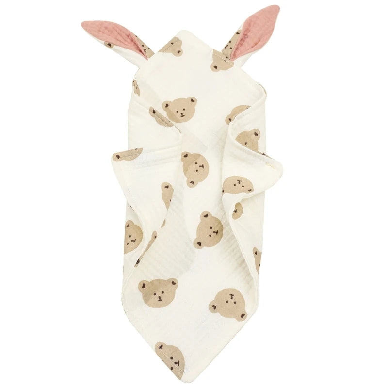 White baby blanket with teddy bear faces and pink bunny ears at the top. The fabric is soft and folded neatly, showcasing a cute and cozy design.