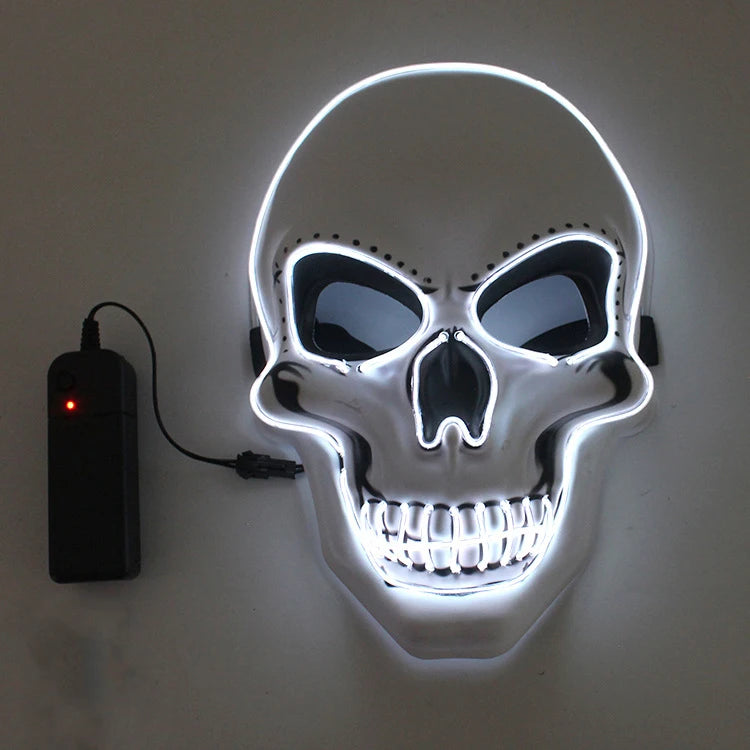 A glowing skull mask with white neon lights outlines its features. Black eye sockets and nose create a stark contrast. A black control unit is connected on the left.