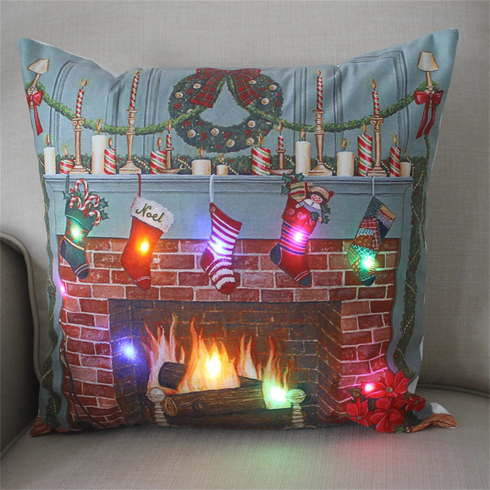 Festive pillow showing a holiday fireplace with stockings, wreath, and lights. The design features a brick mantel with candles and garlands, illuminated by colorful LED lights.