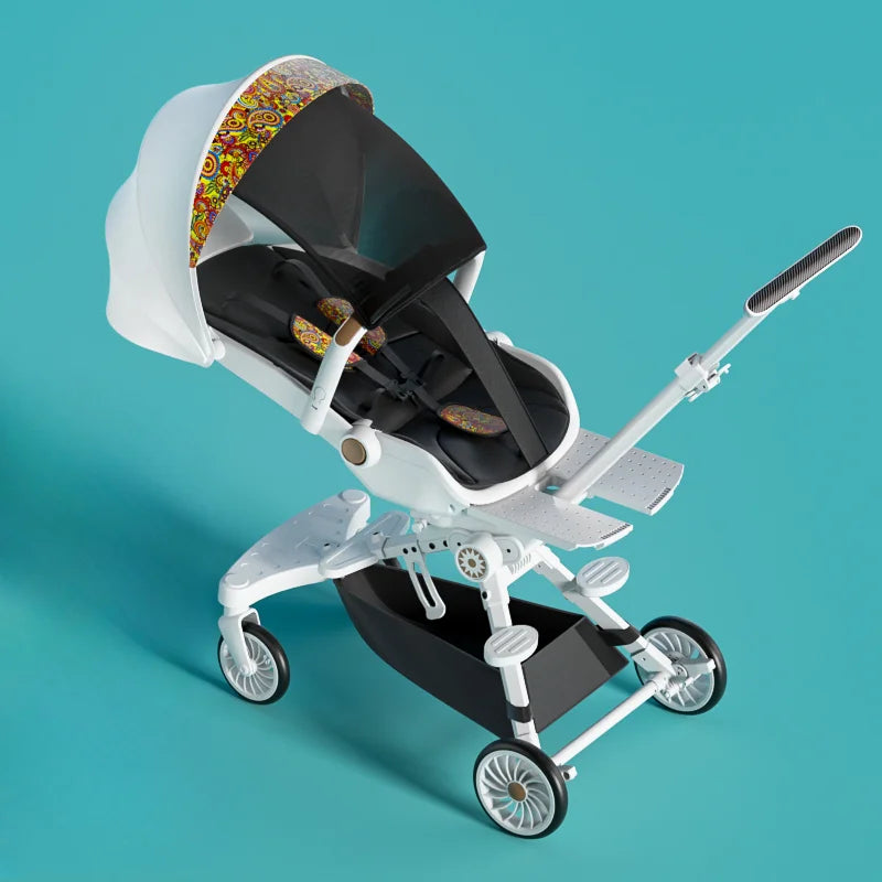 White baby stroller with four wheels, adjustable handle, and colorful patterned canopy on a teal background. Black seat includes colorful cushions and safety straps.