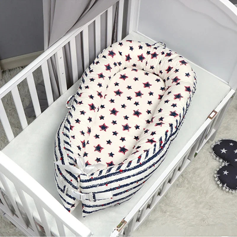 A soft, star-patterned baby lounger with striped sides is placed inside a white crib. A pair of star-themed slippers is visible on the plush carpet next to the crib.