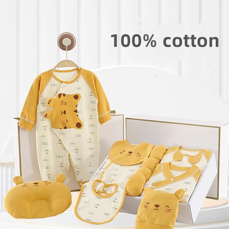 Baby clothing set with yellow and white lion designs, featuring a sleepsuit, bib, mittens, hat, and pillow, displayed in a gift box. Text reads "100% cotton."