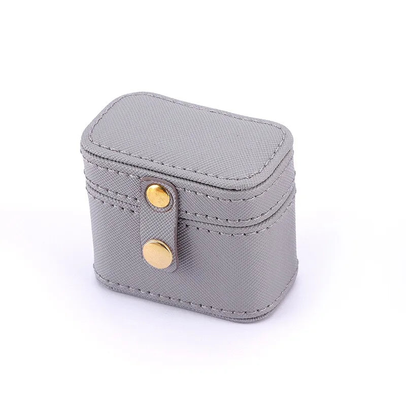 Gray rectangular box with textured surface, featuring a snap closure with two gold buttons. The box has neat stitching details and rounded edges, set on a white background.