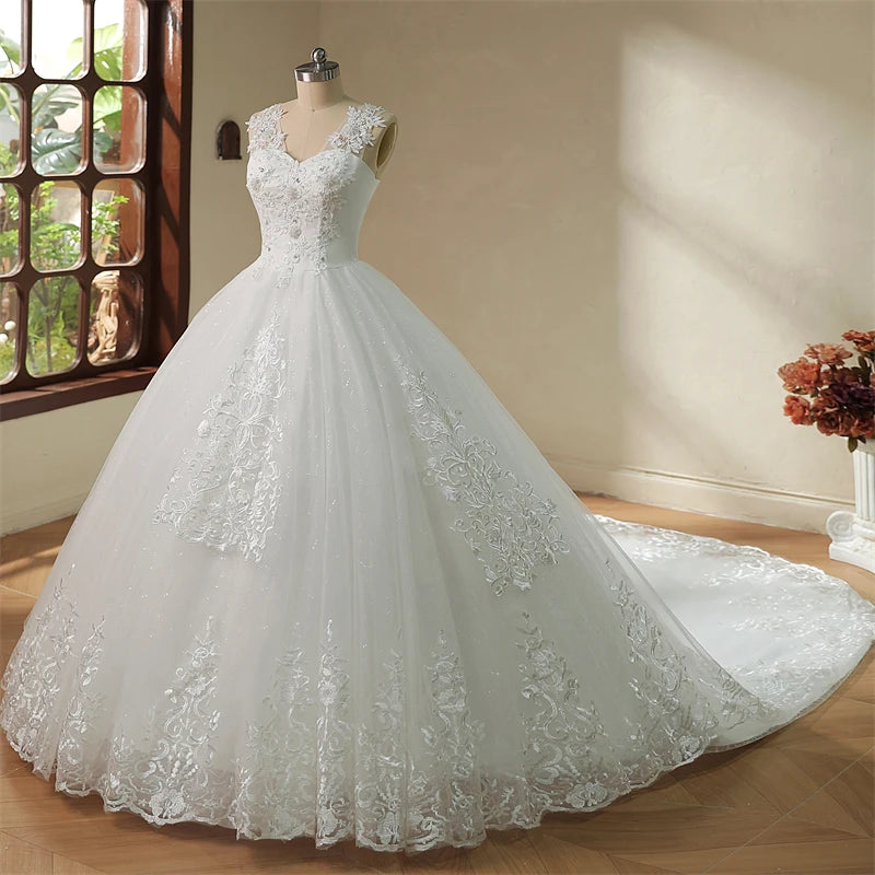 Elegant white wedding gown on a mannequin, featuring lace appliqués and a long, flowing train. The scene is softly lit with sunlight streaming through a nearby window.