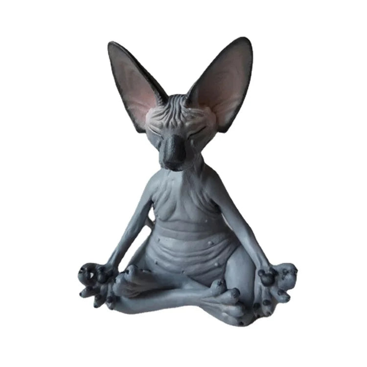 Statue of a hairless cat in a meditative pose, sitting cross-legged, with large ears and serene expression. The figure has a wrinkled body and detailed features.