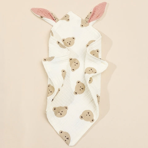 Baby hooded towel with cute bear pattern and pink ears, folded to display the bear faces and ears. The towel is off-white with a soft texture.