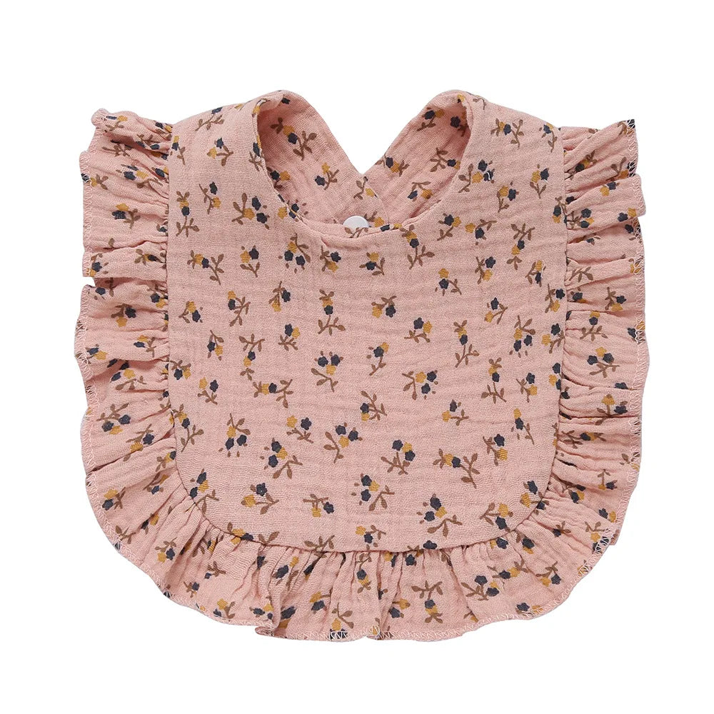 Pink bib with floral pattern and ruffled edges, designed for infants. The fabric is decorated with small blue and brown flowers, adding a touch of charm.