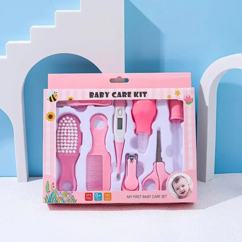 Baby care kit with pink items including a brush, comb, thermometer, dropper, clippers, and scissors, in a decorative box labeled "My First Baby Care Set."